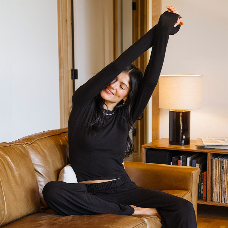 Black Modal Halo Long Sleeve Top, stretching on sofa