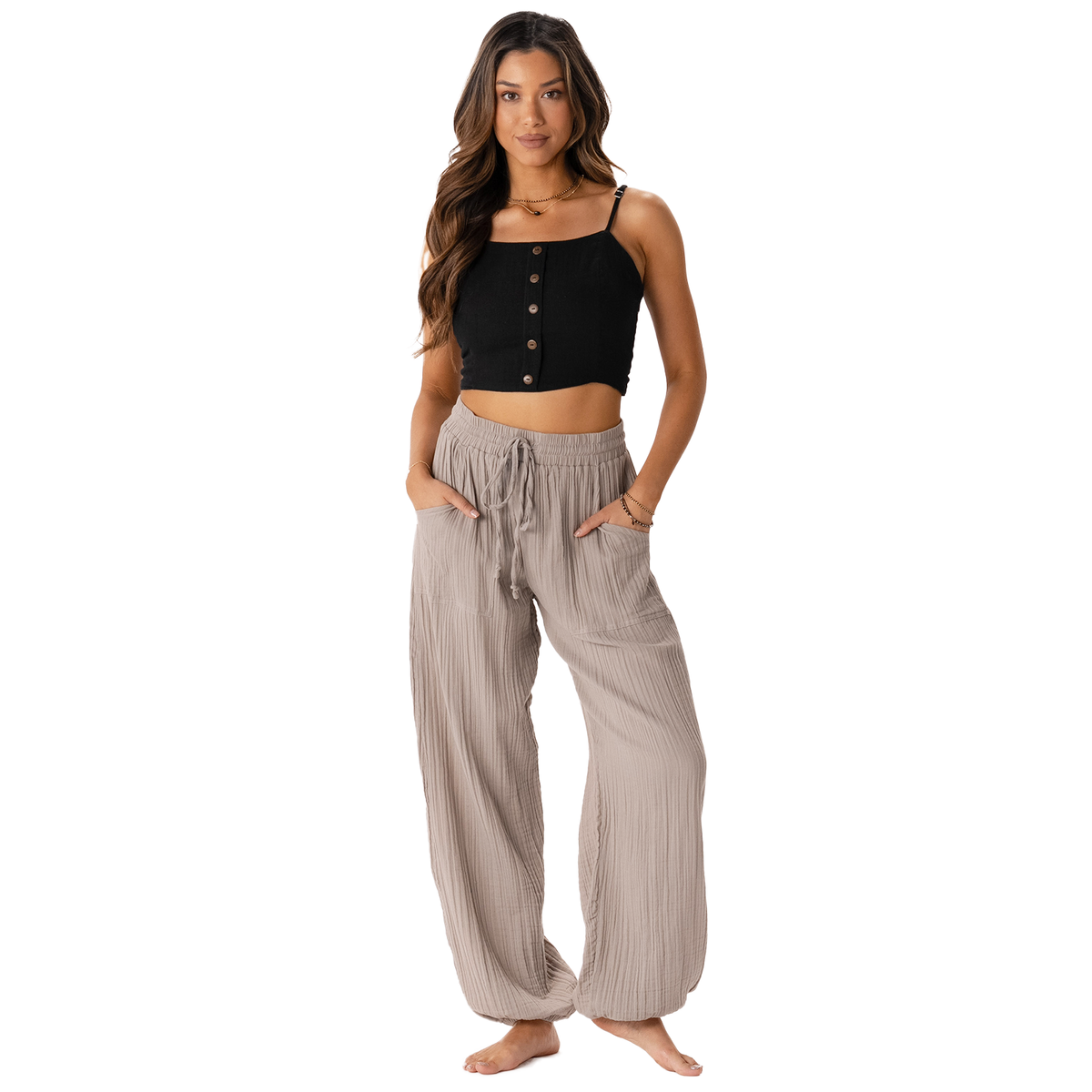 Model wearing stone colored harem pants with a drawstring waistband