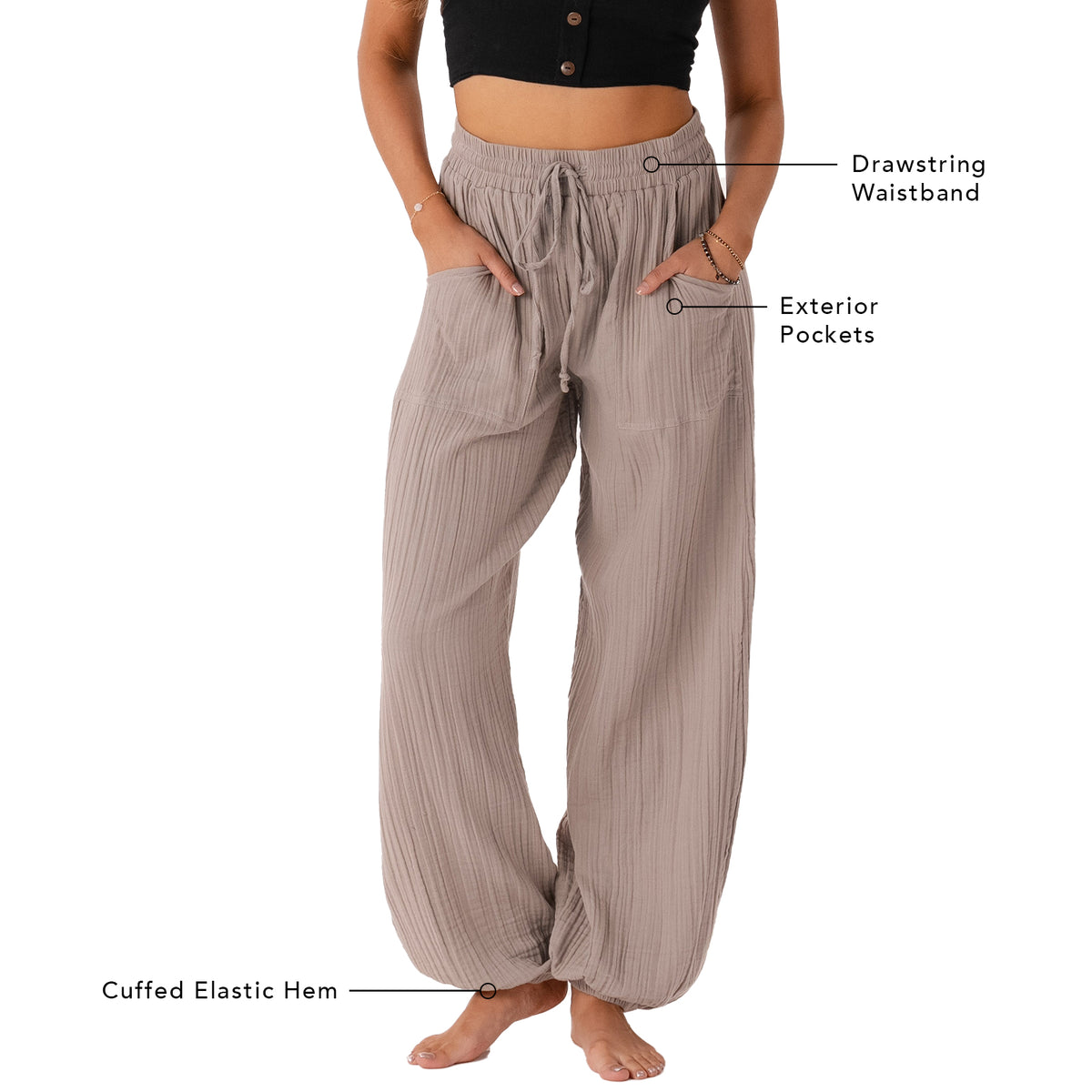 Model wearing stone colored harem pants with a drawstring waistband. The photo outlines the features of the pants including a drawstring waistband, exterior pockets and a cuffed elastic bottom hem