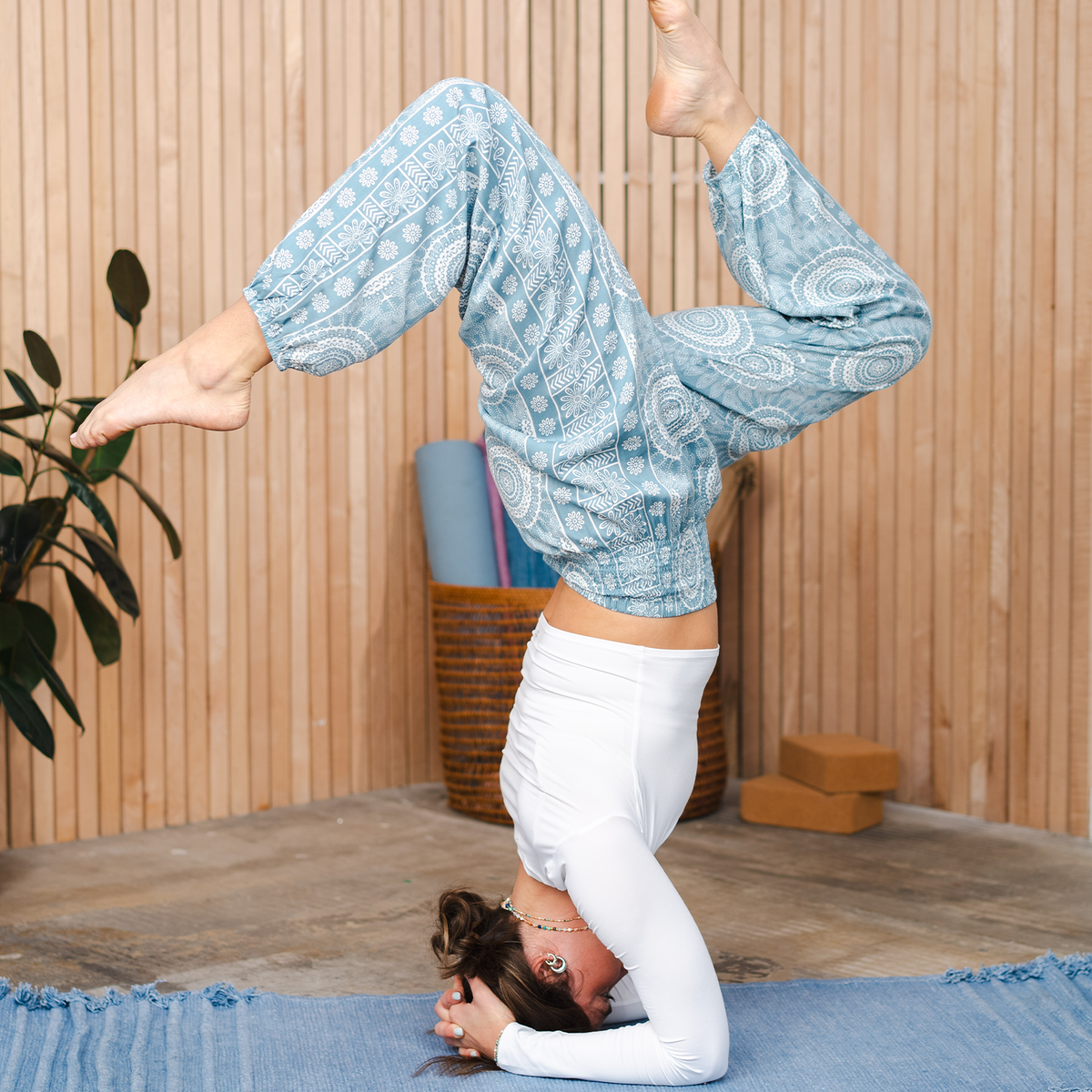 Woman doing a yoga pose wearing light blue and white mandala print harem pants