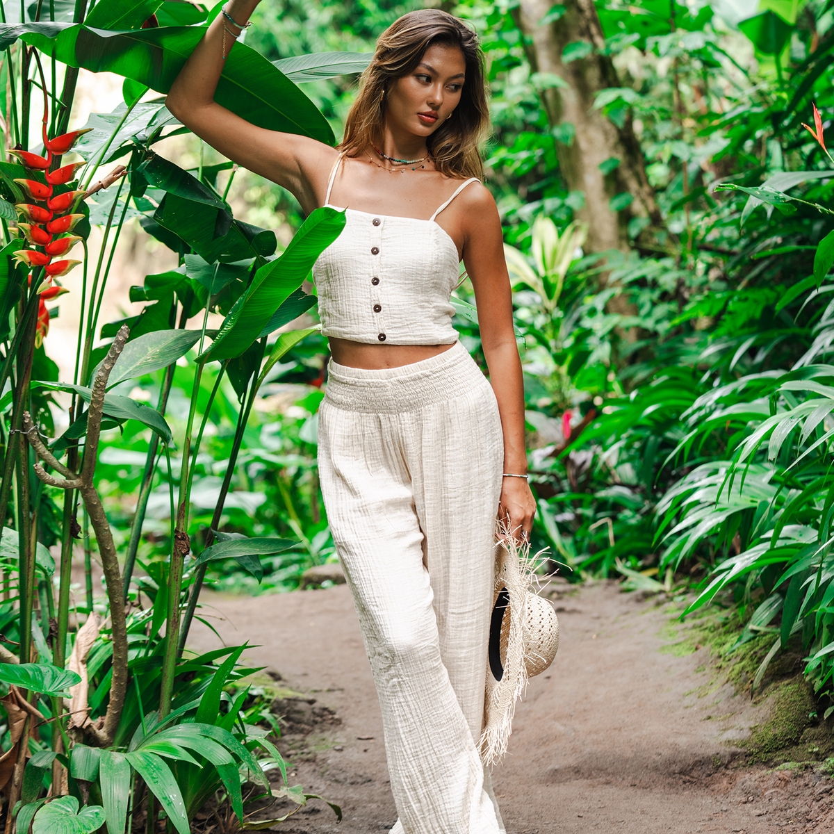 Girl standing in a tropical forest wearing cream wide leg cotton pants and a matching tank top