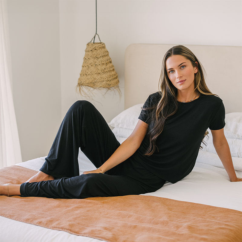 Black Modal Sway Wide Leg Pants, seated on bed