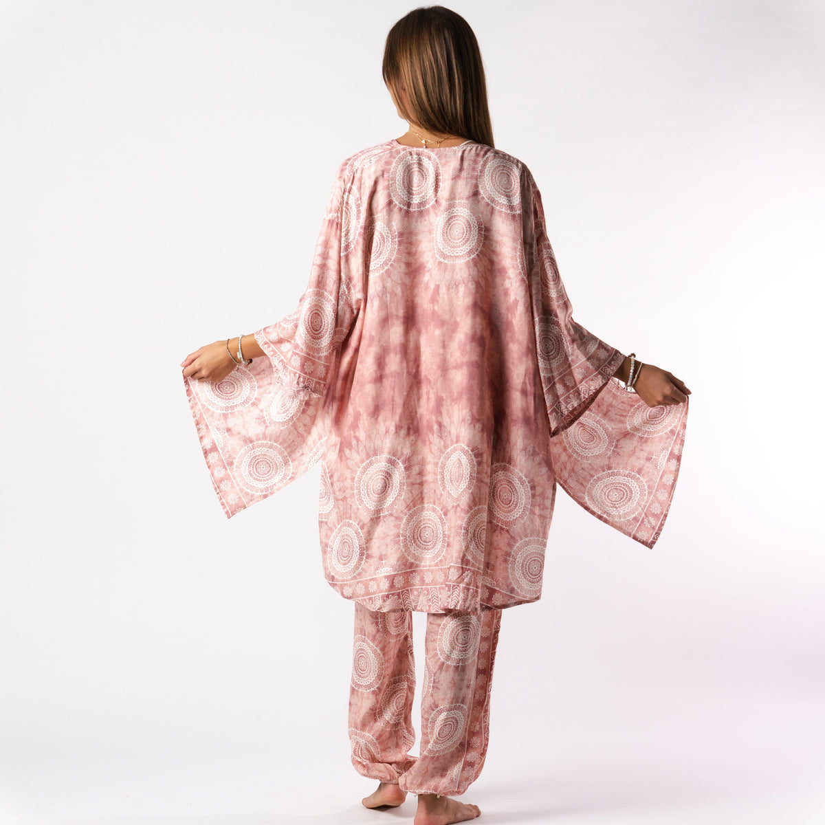 Model wearing a matching lounge set. The set consists of pink and white mandala print harem pants and a matching kimono