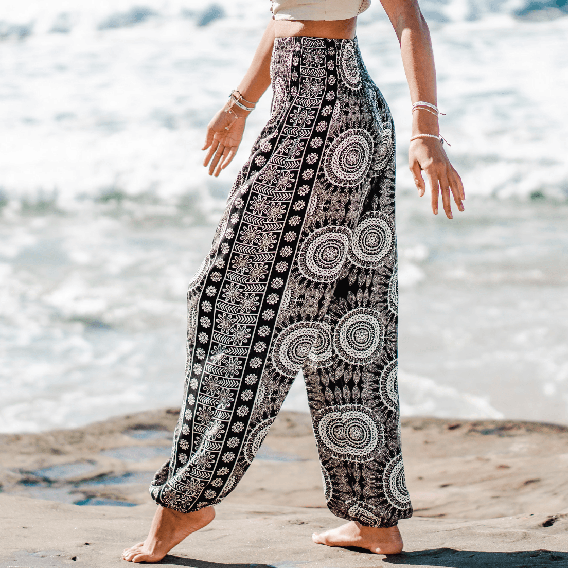 Girl wearing black and cream mandala print harem pants in front of the ocean