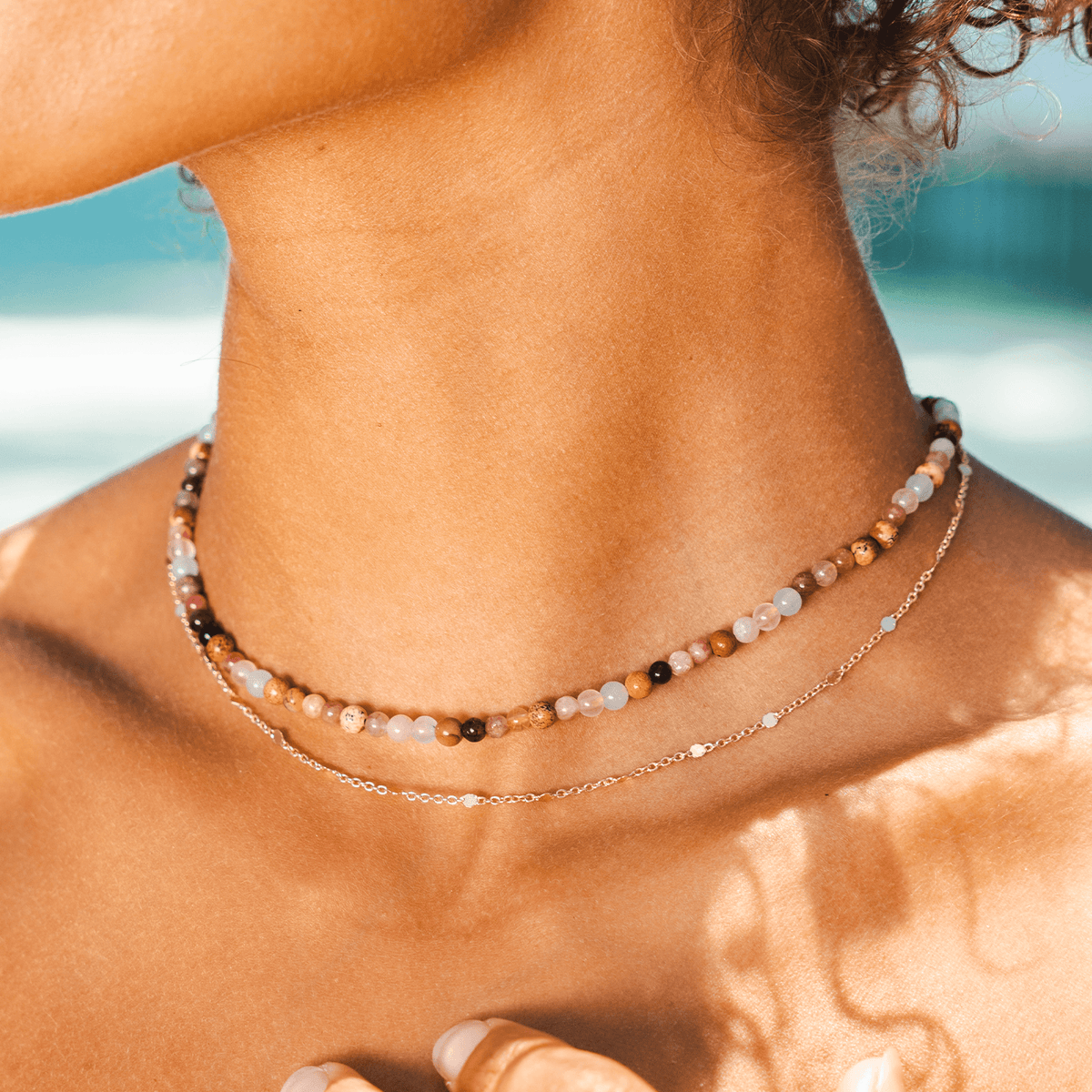 A dainty gold chain necklace paired with a 4mm brown toned bead necklace