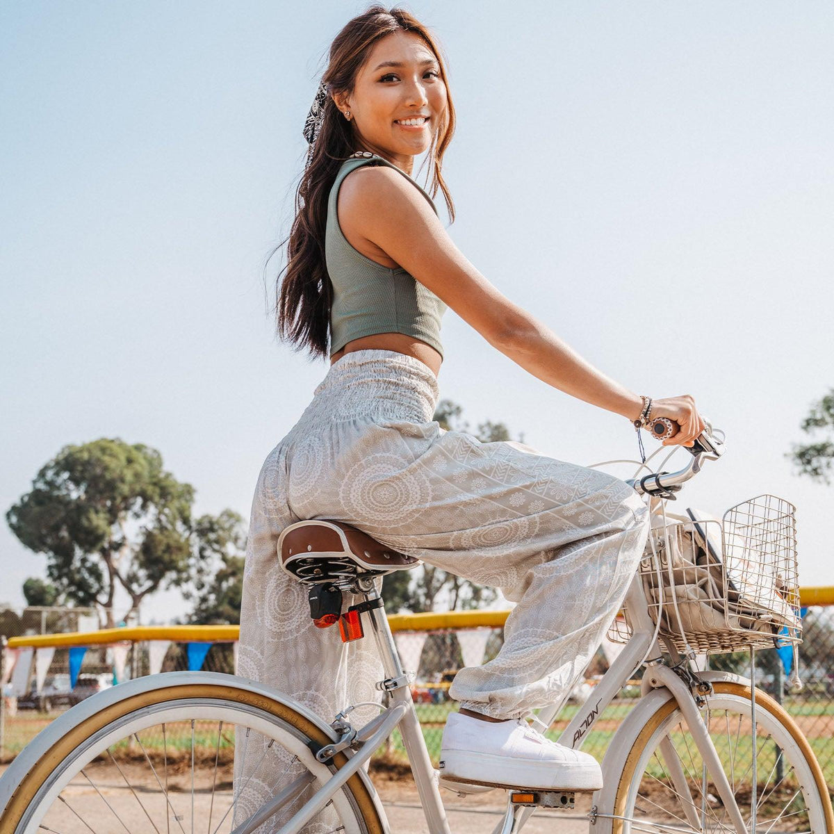 Model riding a bike wearing cream and white mandala print harem pants