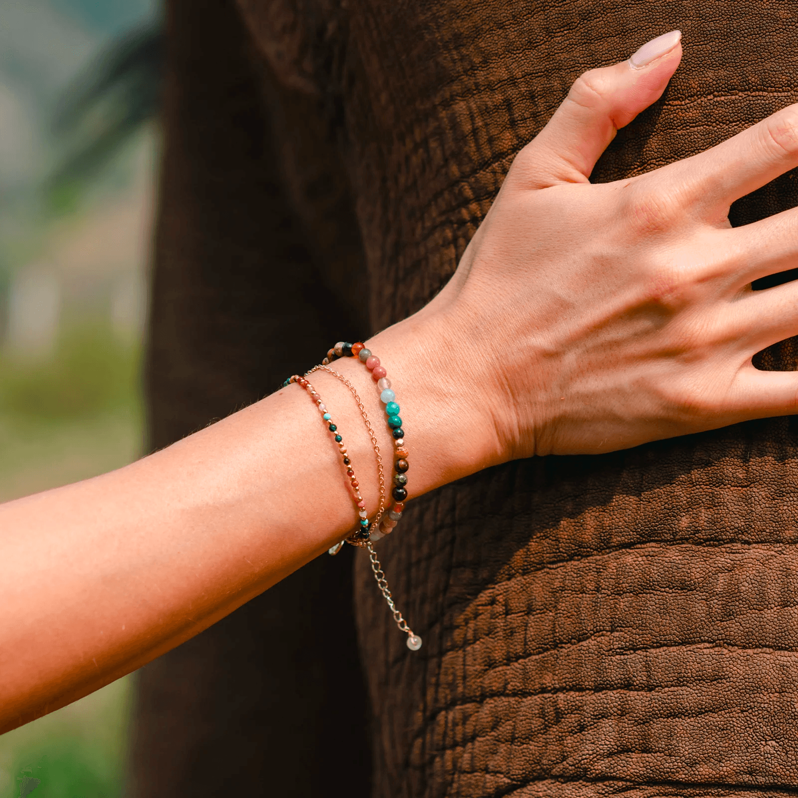 Model wearing a stack of three bracelets. Bracelets include a 4mm multicolor stone bracelet, a 2mm multicolor stone bracelet and a dainty gold chain bracelet